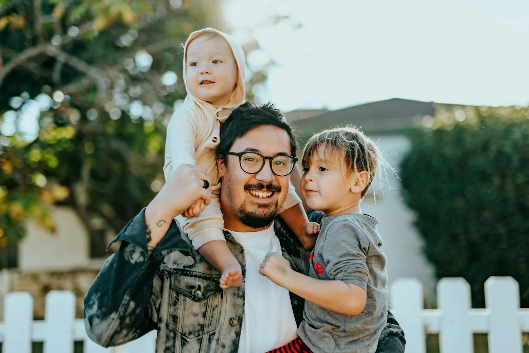 Father carrying his daughter by a white fence
